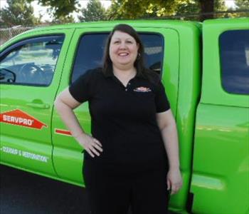 a woman in a black shirt standing in front of a green truck