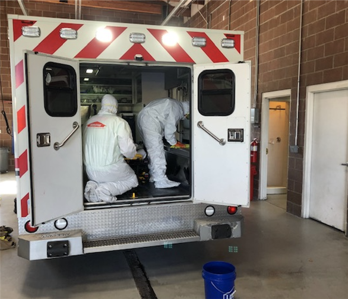2 workers in white suits in a fire truck