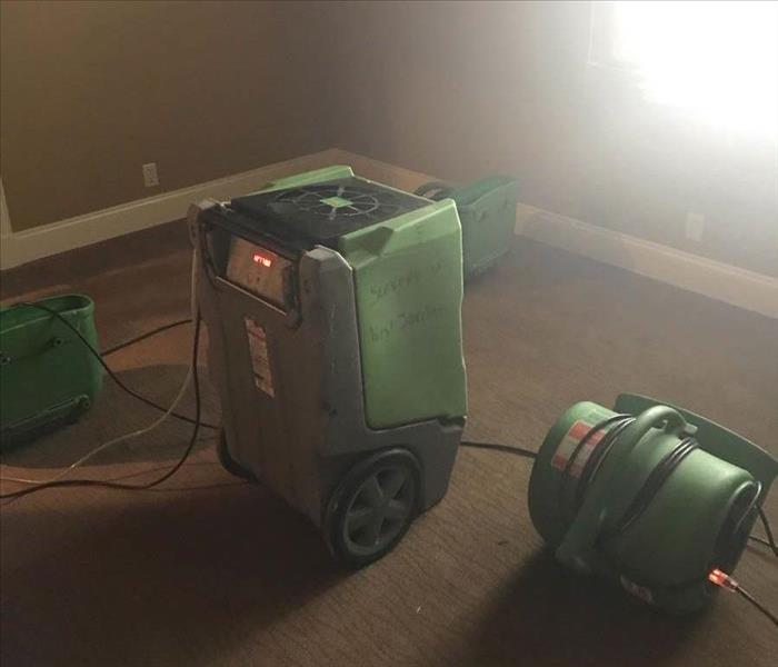 Air movers and dehumidifier set up in a room.